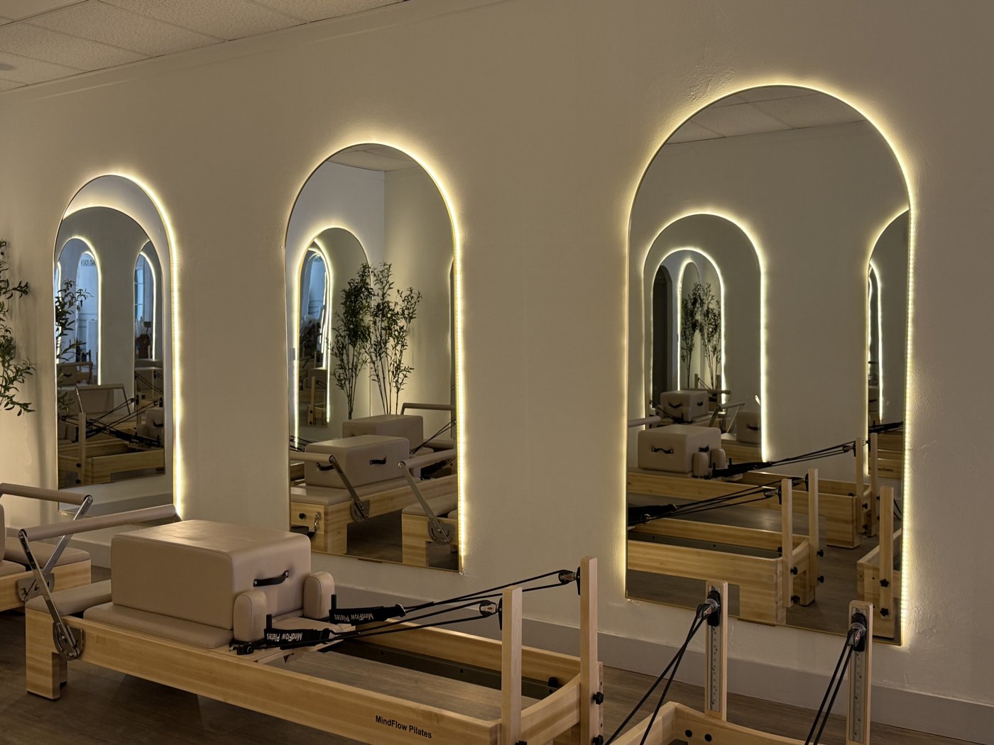 MindFlow Pilates reformers lined up beside backlit arched mirrors