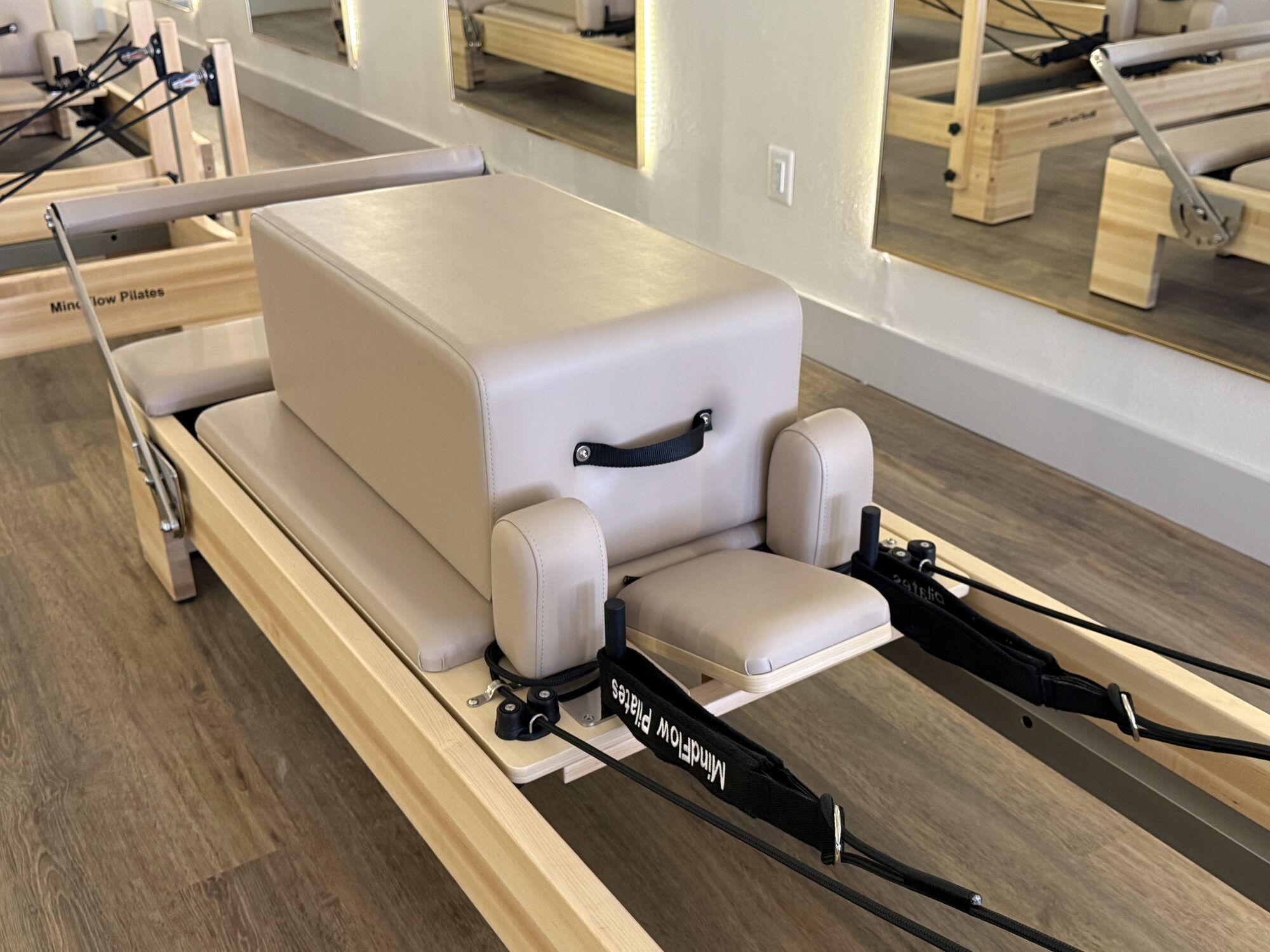 MindFlow Pilates branded reformer set up with a padded box and straps